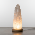 Selenite crystal tower lamp glowing soft white light on wooden base