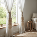 Pair of boho macrame curtain tie-backs in natural cotton rope holding back sheer white curtains