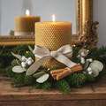 Natural beeswax pillar candle with vanilla and sandalwood scent styled with evergreen sprigs and dried botanicals