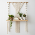 Macrame hanging wall shelf with wooden plank and cotton rope displaying small plants and decor