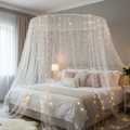 Round hoop bed canopy with sheer white mosquito netting and warm fairy lights in romantic bedroom