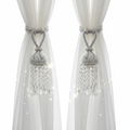 Pair of crystal bead curtain tie-backs with sparkling acrylic droplets holding back sheer curtains